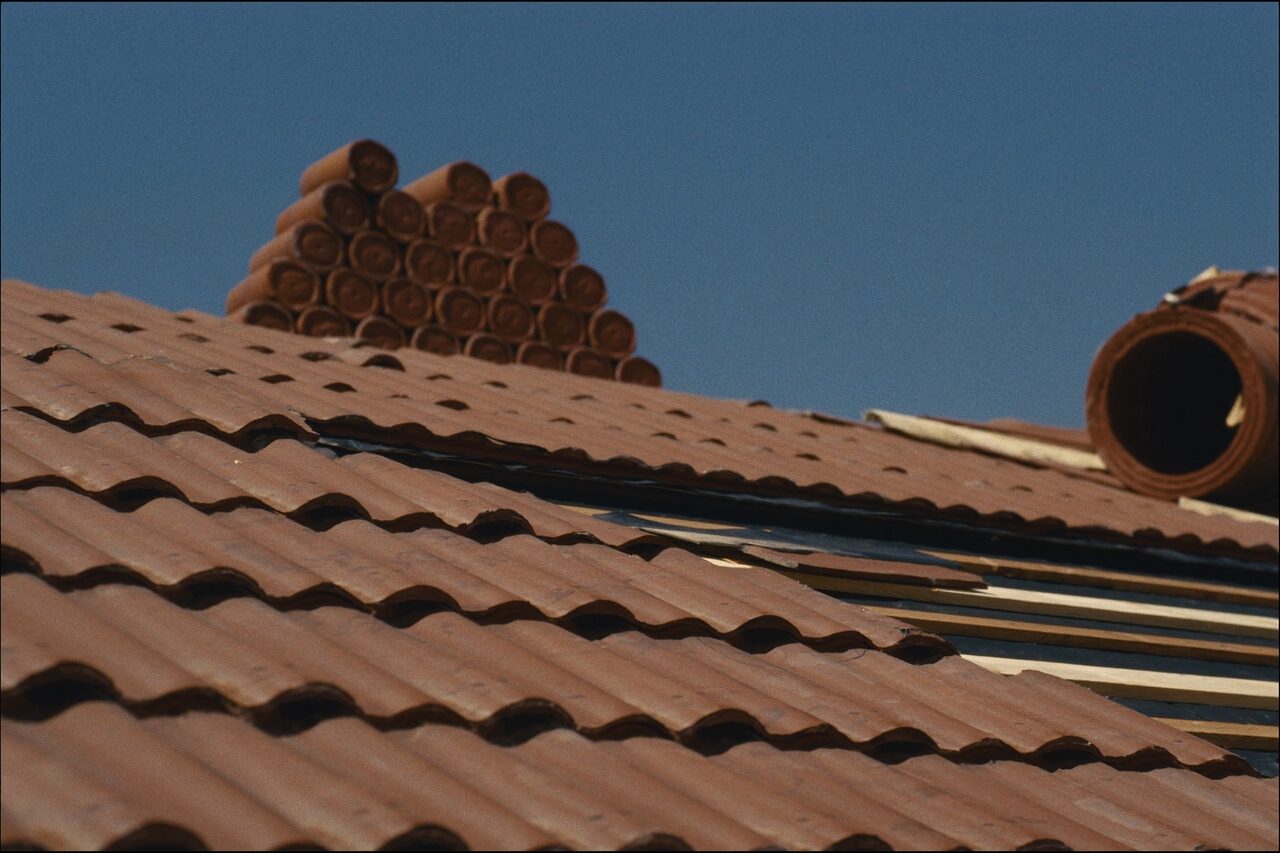 Close-up of clay barrel roof tiles stacked on a tile roof during installation