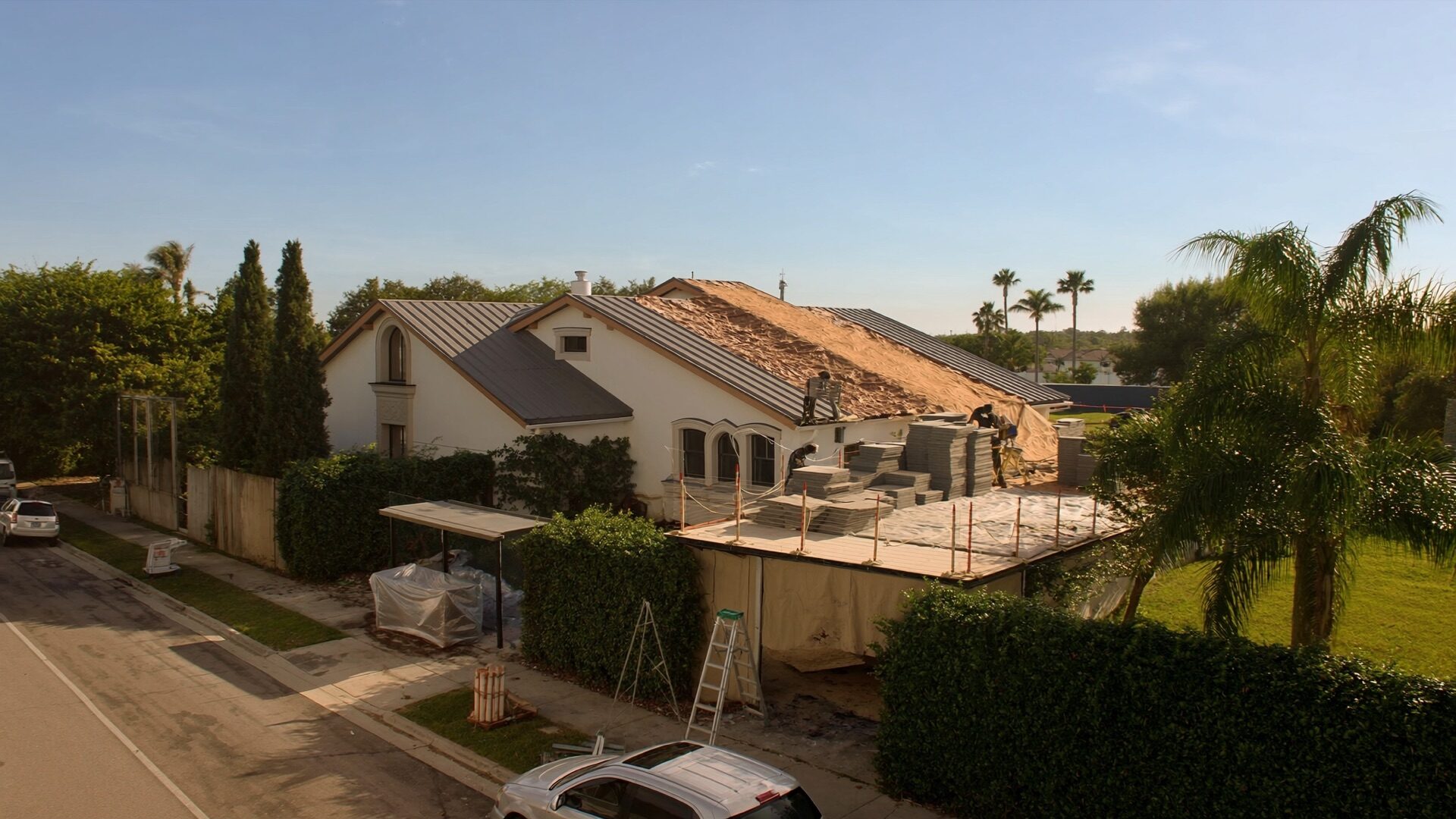 Aerial view of a Florida home being re-roofed, with new decking and stacked tile on site